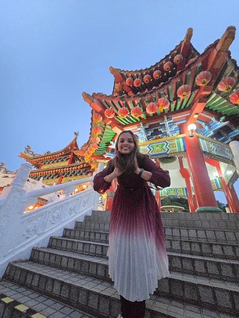 Fazna in front of a red and gold temple gate